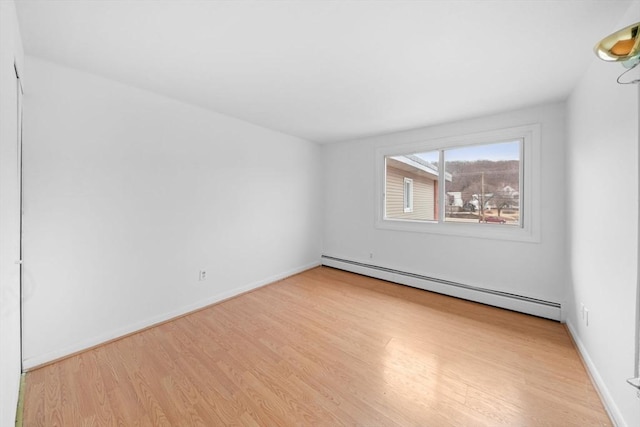 empty room with a baseboard radiator, baseboards, and wood finished floors