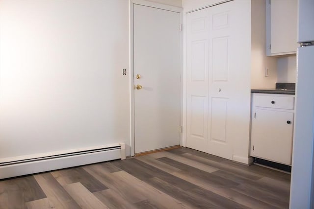 interior space with a baseboard heating unit and wood finished floors