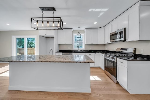 kitchen with recessed lighting, hanging light fixtures, a sink, white cabinetry, and appliances with stainless steel finishes