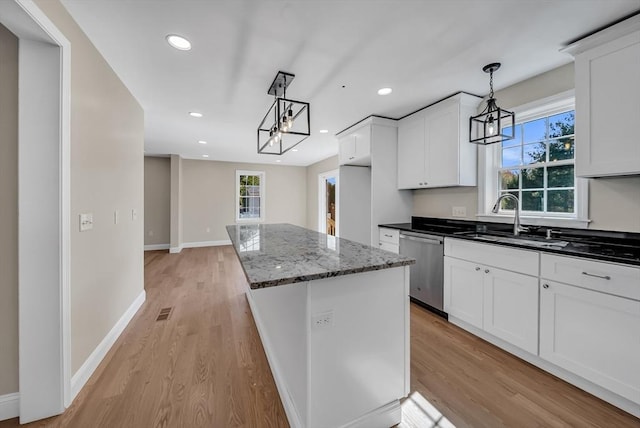 kitchen featuring stainless steel dishwasher, light wood-style floors, an inviting chandelier, and a sink