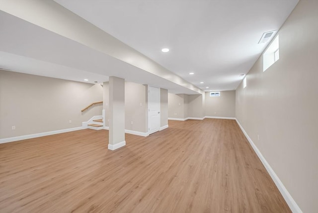 below grade area featuring light wood finished floors, baseboards, stairway, and recessed lighting