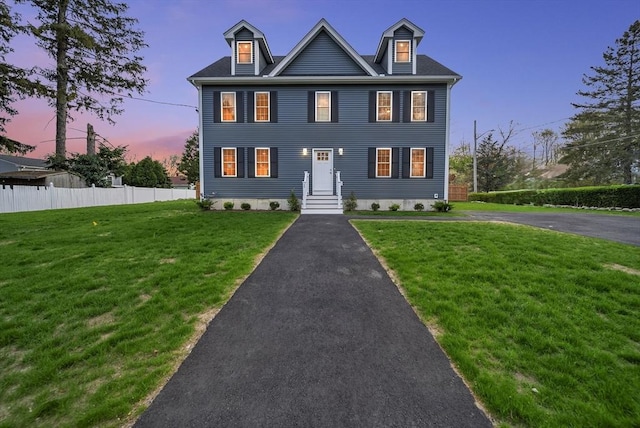colonial home with a front lawn and fence