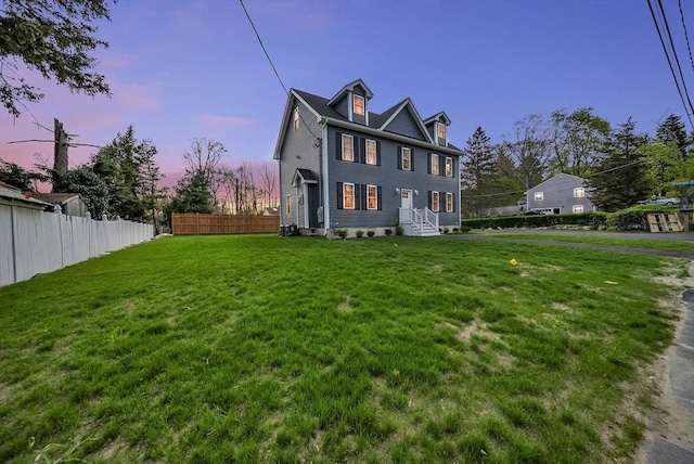 exterior space featuring entry steps, fence, and a front lawn
