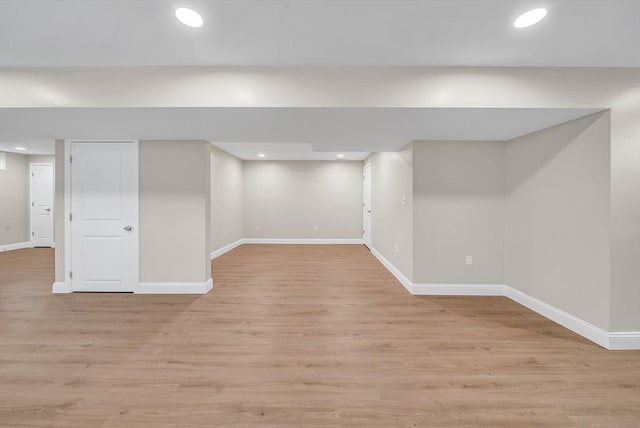 finished below grade area with baseboards, light wood-type flooring, and recessed lighting