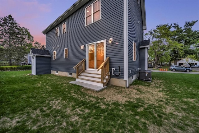 rear view of property featuring central air condition unit, entry steps, and a yard