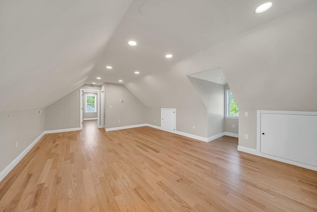 bonus room with plenty of natural light, light wood-style flooring, recessed lighting, vaulted ceiling, and baseboards