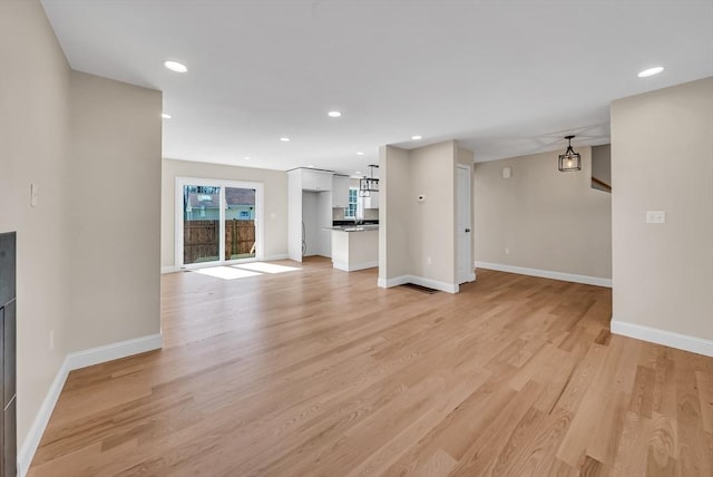 unfurnished living room with light wood finished floors, baseboards, and recessed lighting