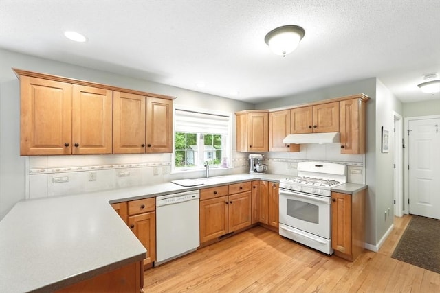 167 Orchard Rd, East Longmeadow, MA 01028 - kitchen featuring white appliances, light wood-style flooring, under cabinet range hood, tasteful backsplash, and light countertops
