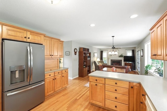 167 Orchard Rd, East Longmeadow, MA 01028 - kitchen with stainless steel fridge, a peninsula, a fireplace, open floor plan, and light wood-style flooring