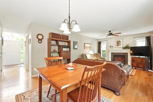 167 Orchard Rd, East Longmeadow, MA 01028 - dining area with light wood-type flooring, a chandelier, a ceiling fan, and a glass covered fireplace
