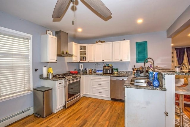 37 Border St, Springfield, MA 01104 - kitchen with stainless steel appliances, wall chimney exhaust hood, baseboard heating, a peninsula, and light wood-style flooring