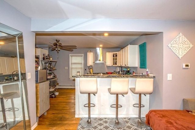 37 Border St, Springfield, MA 01104 - kitchen with wall chimney exhaust hood, a peninsula, glass insert cabinets, ceiling fan, and wood finished floors