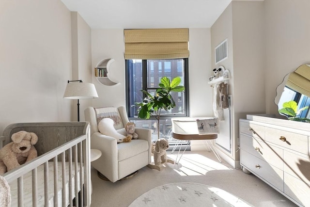 bedroom with a crib, multiple windows, visible vents, and carpet flooring