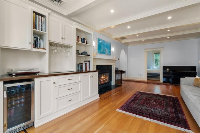 19 Woodbine St Unit B, Newton, MA 02466 - living area featuring beverage cooler, light wood-type flooring, beam ceiling, a glass covered fireplace, and arched walkways
