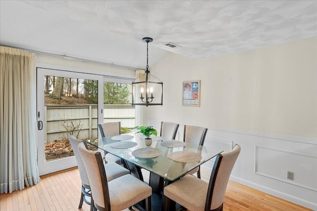 dining room with visible vents, an inviting chandelier, lofted ceiling, light wood-style floors, and a textured ceiling