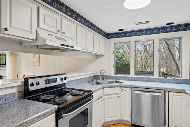 kitchen with light countertops, under cabinet range hood, white cabinets, a sink, and stainless steel appliances