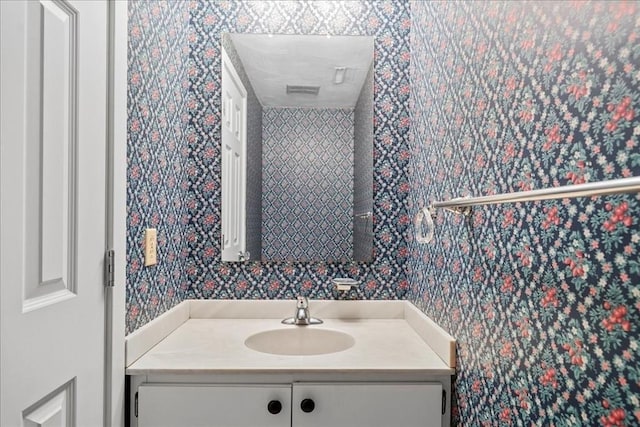 bathroom featuring vanity and wallpapered walls