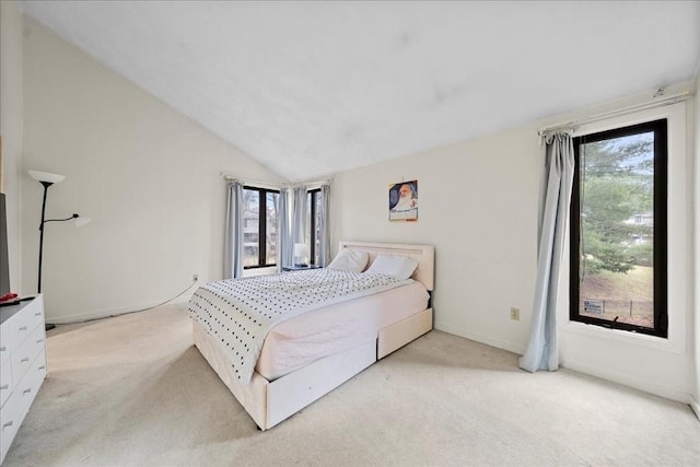 bedroom with baseboards, vaulted ceiling, light carpet, and multiple windows
