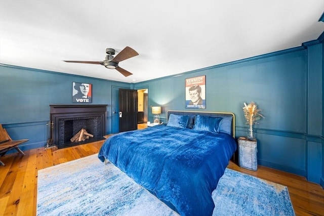 46 Church St, Dedham, MA 02026 - bedroom featuring crown molding, ceiling fan, a fireplace with flush hearth, wood finished floors, and a decorative wall