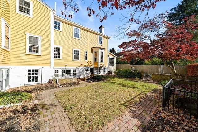 46 Church St, Dedham, MA 02026 - rear view of property featuring entry steps, fence, a lawn, and a chimney