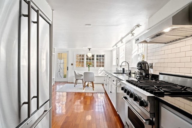 46 Church St, Dedham, MA 02026 - kitchen featuring a sink, decorative backsplash, stainless steel appliances, wood-type flooring, and wall chimney range hood