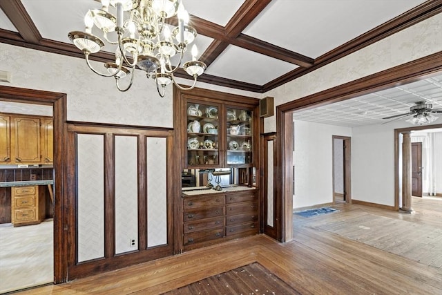 unfurnished dining area with beamed ceiling, ceiling fan with notable chandelier, light hardwood / wood-style flooring, and coffered ceiling