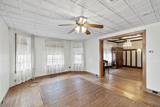 empty room with wood-type flooring and ceiling fan with notable chandelier