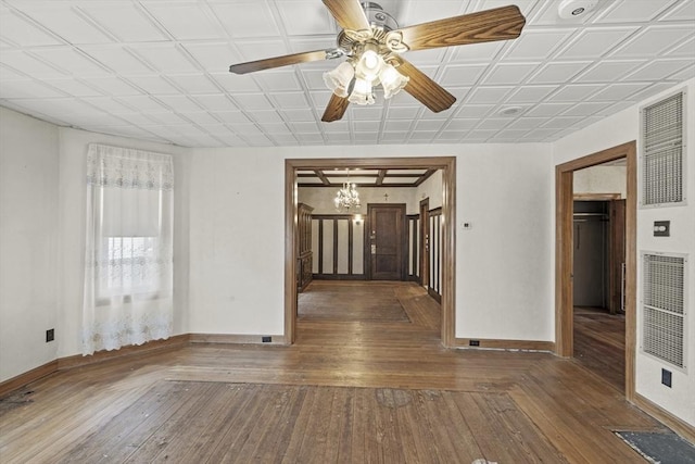 empty room featuring ceiling fan with notable chandelier and dark hardwood / wood-style flooring