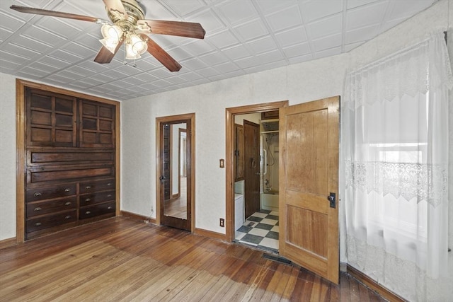 unfurnished bedroom with ensuite bathroom, hardwood / wood-style floors, and ceiling fan