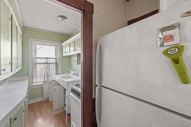 kitchen with light hardwood / wood-style floors, white appliances, and sink