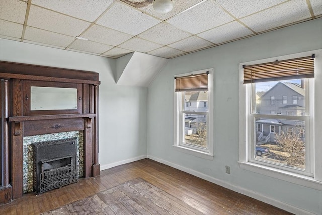 unfurnished living room featuring hardwood / wood-style floors, a drop ceiling, and a high end fireplace