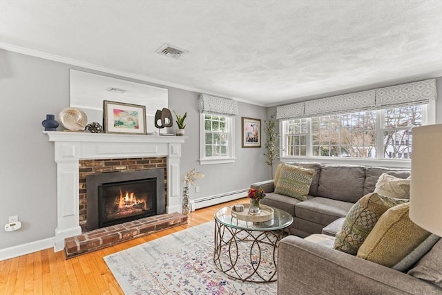 living room with visible vents, a baseboard radiator, light wood-style flooring, ornamental molding, and a fireplace