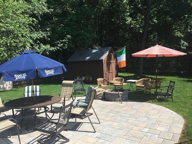 view of patio / terrace with a shed, a fire pit, an outdoor structure, and outdoor dining space