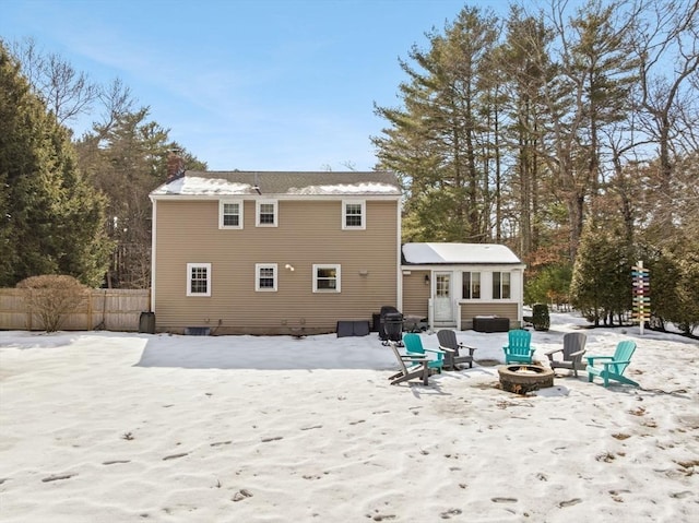 snow covered property with a fire pit, a chimney, and fence