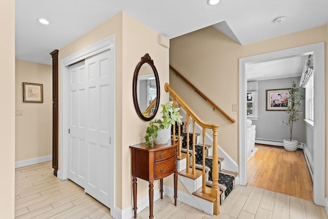 entrance foyer featuring a baseboard radiator, light wood-style flooring, and baseboards