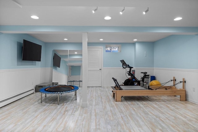 exercise area featuring baseboard heating and light hardwood / wood-style flooring