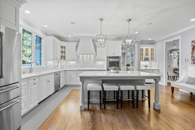 kitchen featuring premium range hood, white cabinetry, appliances with stainless steel finishes, and a center island