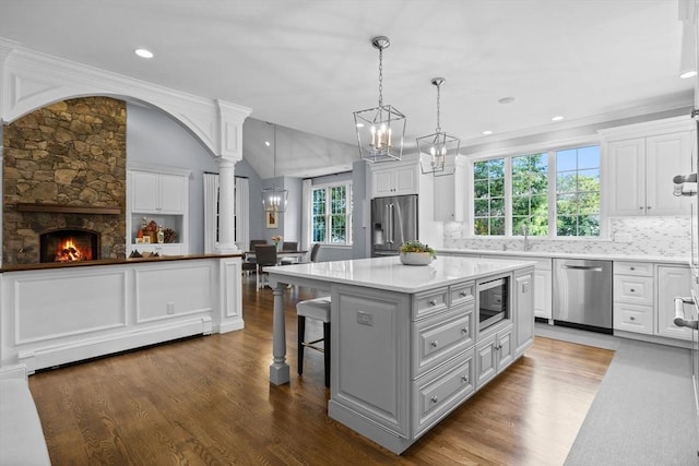 kitchen featuring white cabinetry, a center island, pendant lighting, and appliances with stainless steel finishes