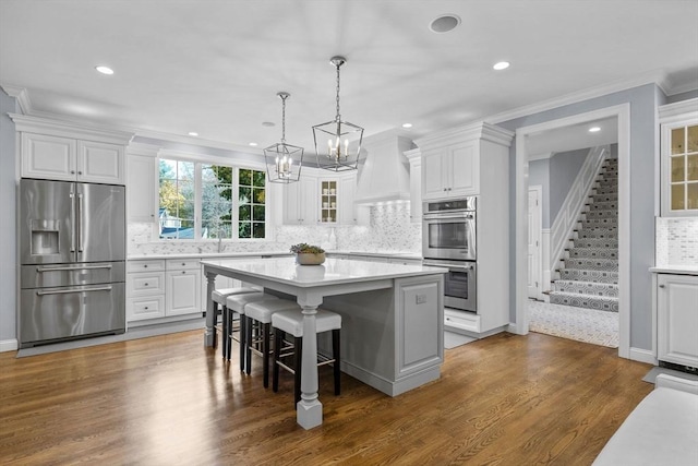 kitchen with white cabinets, a kitchen bar, a center island, dark hardwood / wood-style floors, and stainless steel appliances