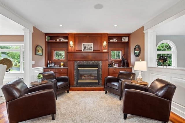 living room featuring built in features, decorative columns, and a healthy amount of sunlight