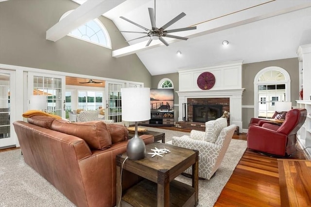 living room featuring a brick fireplace, light hardwood / wood-style flooring, high vaulted ceiling, and ceiling fan