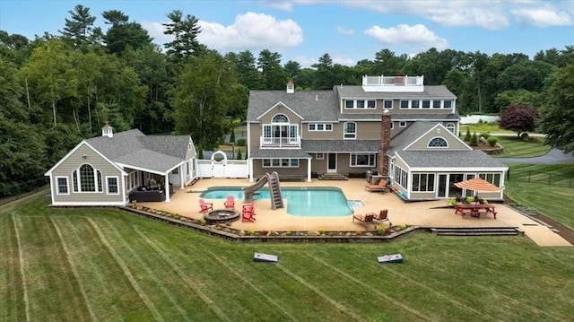 rear view of house with a sunroom, a yard, a patio area, and a fire pit