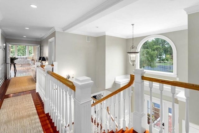 corridor featuring crown molding, wood-type flooring, and an inviting chandelier