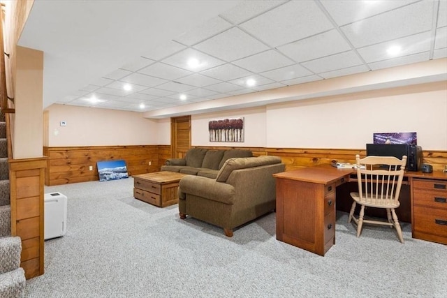 living room featuring a paneled ceiling, light colored carpet, and wood walls