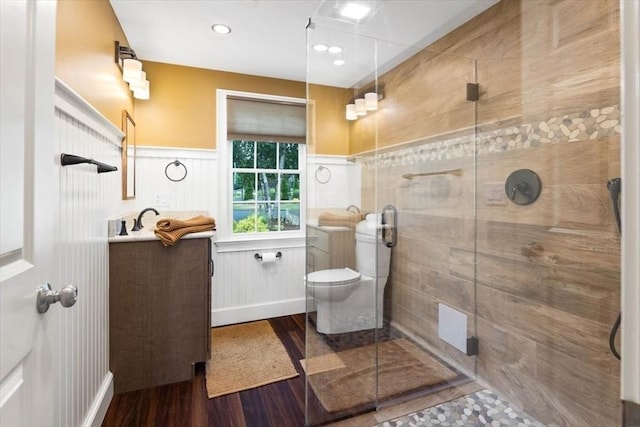 bathroom featuring vanity, hardwood / wood-style flooring, a shower with shower door, and toilet