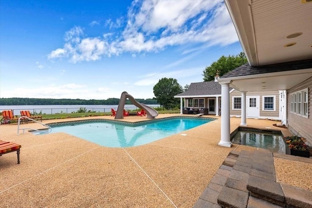 view of swimming pool featuring a water view, a patio, a water slide, and an outbuilding