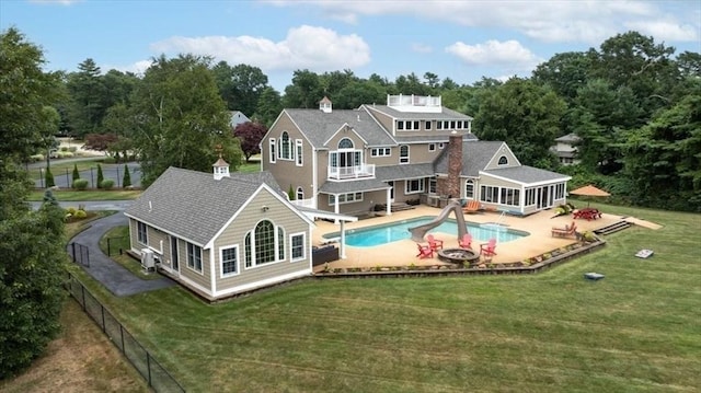 back of house with a yard, a fenced in pool, a patio area, and a sunroom