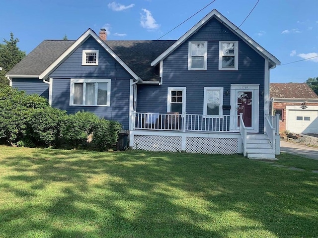 view of front of house featuring covered porch, a shingled roof, a chimney, and a front yard