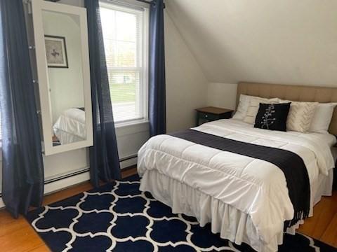 bedroom with a baseboard radiator, vaulted ceiling, and dark hardwood / wood-style floors