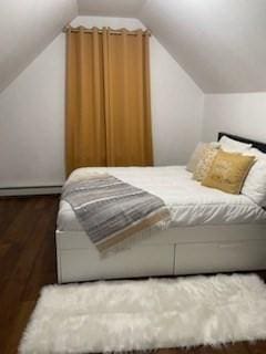 bedroom featuring vaulted ceiling, a baseboard radiator, and dark hardwood / wood-style floors